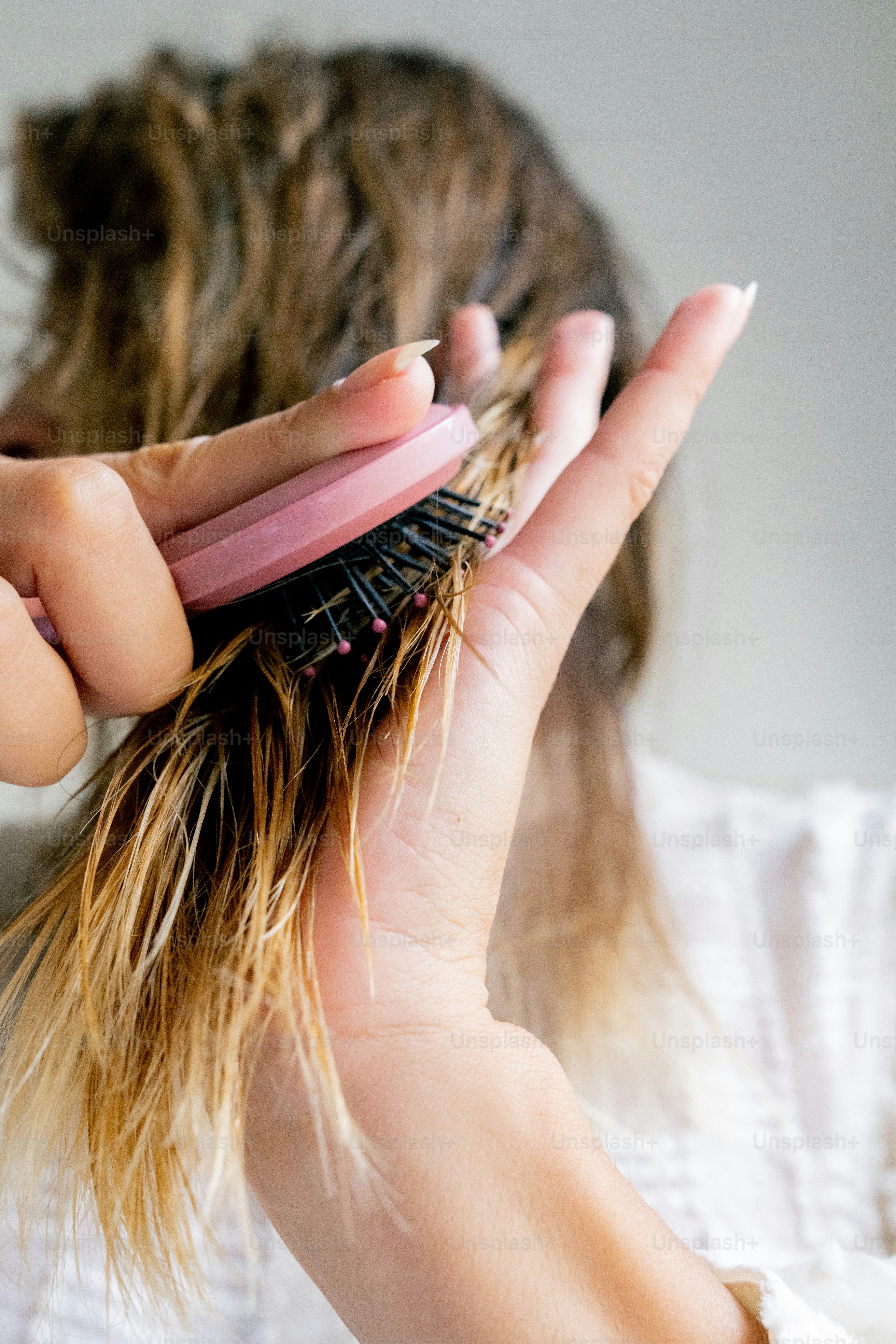 A woman is brushing her hair with a brush